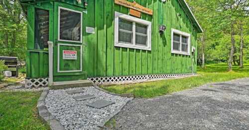 A bright green cabin with white trim, surrounded by trees and a gravel path leading to the entrance.