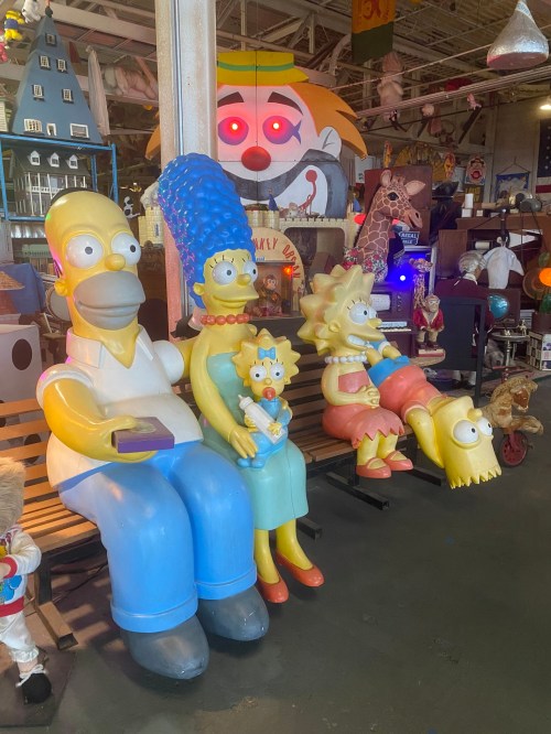 A colorful display featuring large, cartoonish figures of the Simpson family sitting together in a whimsical setting.