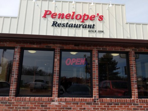 Exterior of Penelope's Restaurant, featuring a brick facade and an "OPEN" sign in the window. Established in 1996.