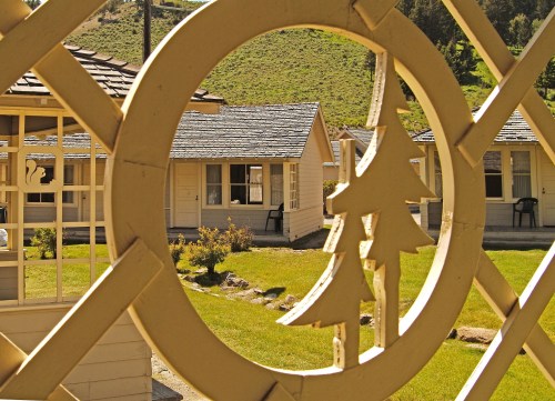 A view through a decorative frame showing small cabins in a green landscape.