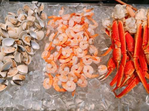 A display of seafood on ice, featuring clams, shrimp, and crab legs.