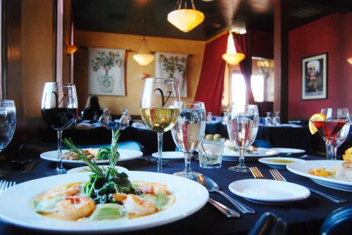 A beautifully set dining table with various drinks and a gourmet shrimp dish in a cozy restaurant ambiance.