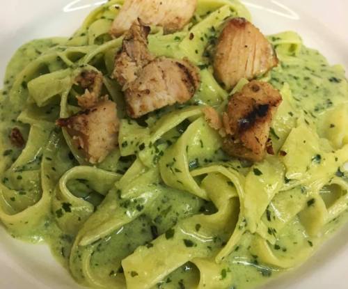 Creamy green fettuccine pasta topped with grilled chicken pieces.