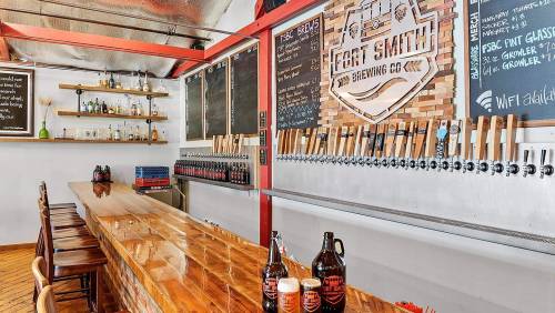 A modern brewery interior featuring a wooden bar, beer taps, and a chalkboard menu on the wall.