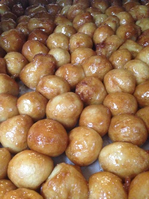 A close-up of golden, glossy dough balls arranged closely together, glistening with a sweet glaze.