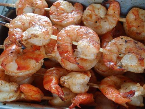 Grilled shrimp skewers arranged in a tray, showcasing a golden-brown, charred appearance.