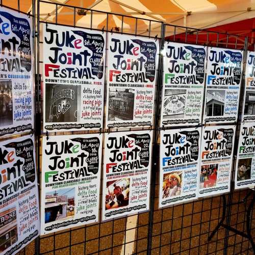 A display of colorful posters for the Juke Joint Festival, featuring event details and images of local attractions.