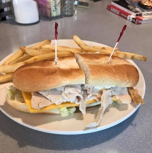 A sandwich with turkey and cheese on a plate, accompanied by a side of French fries.