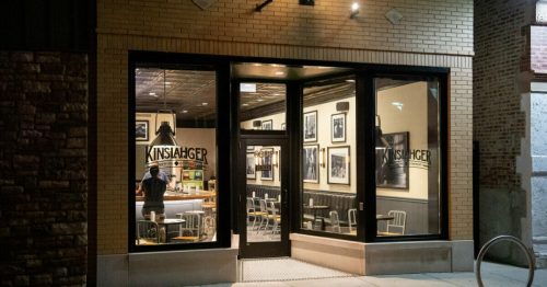 Exterior view of Kinslahger restaurant at night, featuring large windows and a warm, inviting atmosphere.