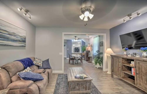 Cozy living room with a sofa, coffee table, and TV, leading to a dining area with a table and plants.