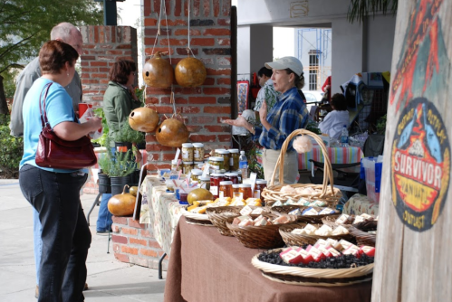 A market scene with vendors selling jars, baked goods, and decorative gourds, while customers browse and chat.