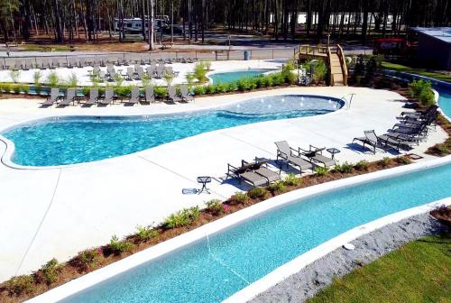 Aerial view of a resort-style pool area with lounge chairs, a lazy river, and surrounded by trees.
