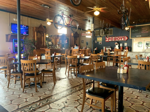 A spacious restaurant with wooden tables and chairs, vintage decor, and bicycles hanging from the ceiling.