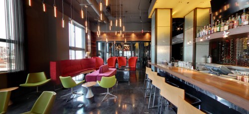 Modern lounge with colorful seating, a sleek bar, and stylish lighting, creating a vibrant atmosphere.