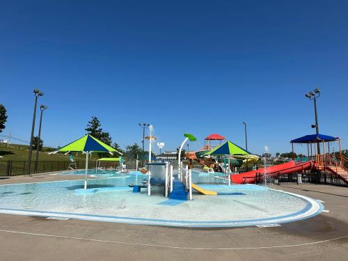A vibrant water park featuring splash pads, colorful umbrellas, and water slides under a clear blue sky.