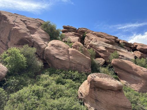 Rocky formations with green shrubs under a blue sky, showcasing natural landscape features.