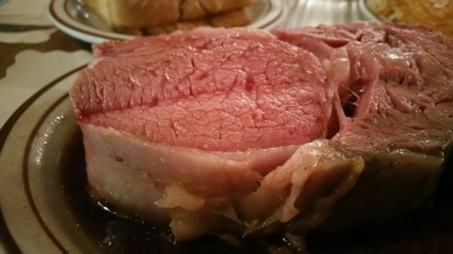 A close-up of a juicy, medium-rare roast beef slice on a plate, showcasing its pink interior and marbled texture.