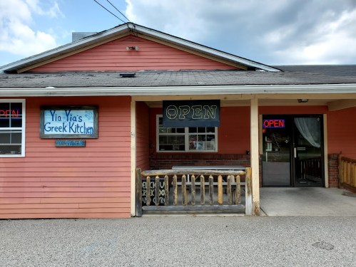 A pink building with a sign reading "Yia Yia's Greek Kitchen" and an "OPEN" sign in the window.