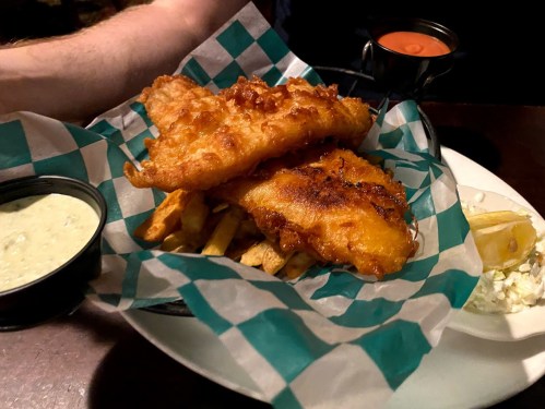 A plate of crispy fish and fries, served with a side of tartar sauce and a lemon wedge.