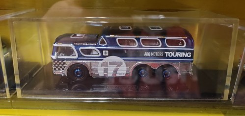 A miniature model of a vintage bus displayed in a clear case, featuring blue and silver colors with "ABQ Motors Touring" text.