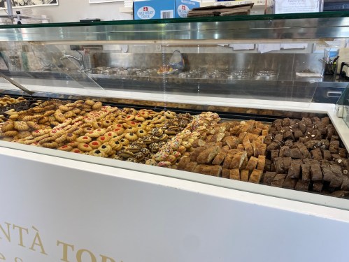 A display case filled with a variety of colorful cookies and pastries, showcasing an assortment of baked goods.