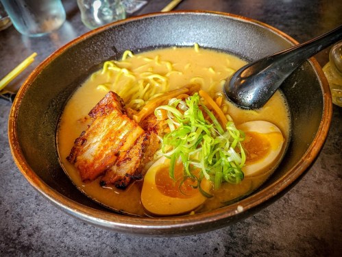 A bowl of ramen with broth, noodles, sliced pork, green onions, and soft-boiled eggs.