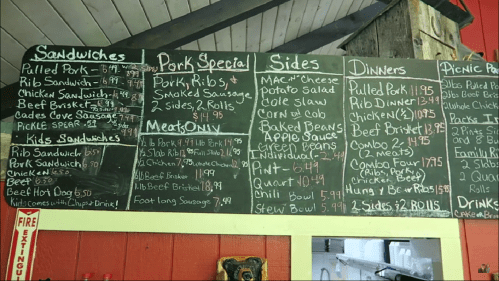 Menu board featuring sandwiches, pork specials, sides, and dinner options with prices listed.