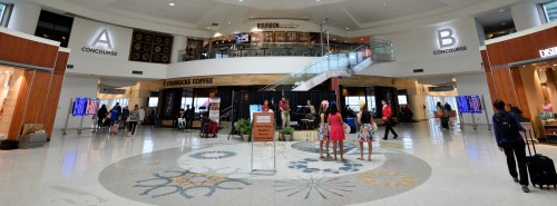 A spacious airport terminal with two concourses labeled A and B, featuring shops, seating areas, and travelers.