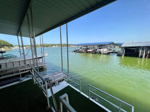 View of a calm lake with boat docks and clear blue skies, framed by a covered patio.