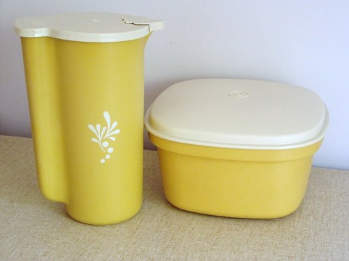 Two yellow kitchen containers: a tall pitcher with a spout and a square storage box with a white lid.