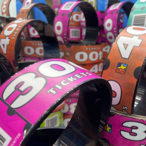 Colorful carnival tickets stacked together, featuring numbers and designs in pink, blue, and orange.