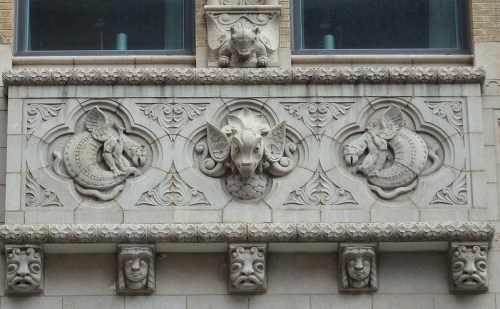 Architectural relief featuring intricate carvings of mythical creatures and faces on a building facade.
