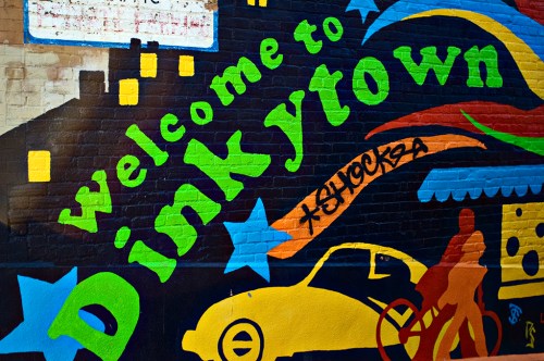 Colorful mural reading "Welcome to Dinkytown" with vibrant designs and silhouettes of a car and people.