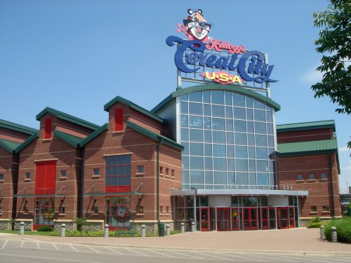 Exterior of Kellogg's Cereal City USA, featuring a large sign and a modern brick building under a clear blue sky.