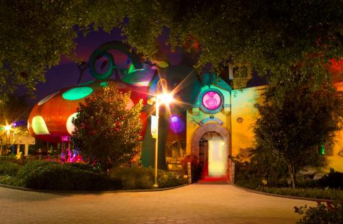 Colorful, whimsical building at night, surrounded by trees and vibrant lights, creating a magical atmosphere.