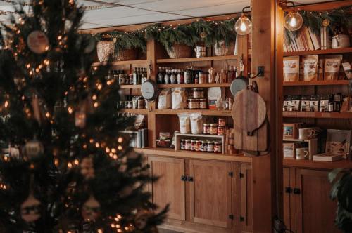 Cozy shop interior with wooden shelves filled with jars and products, decorated for the holidays with a Christmas tree.