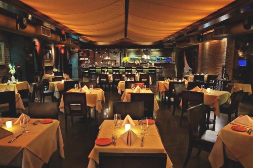 Elegant restaurant interior with tables set for dining, soft lighting, and a cozy atmosphere.