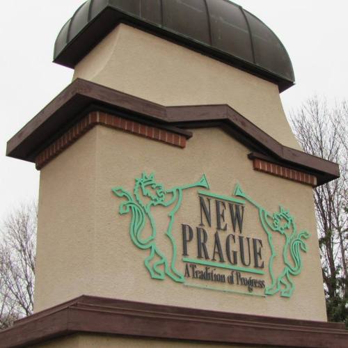 Sign for New Prague featuring two lion designs and the tagline "A Tradition of Progress."