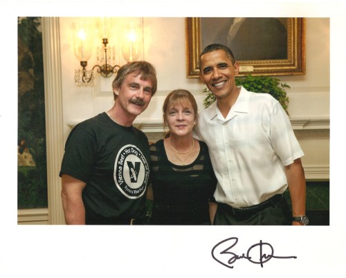 A man and a woman pose with a smiling man in a white shirt, in a well-lit indoor setting.