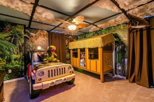 A themed children's bedroom with a Jeep bed, dinosaur decor, and a playhouse-style bunk bed.