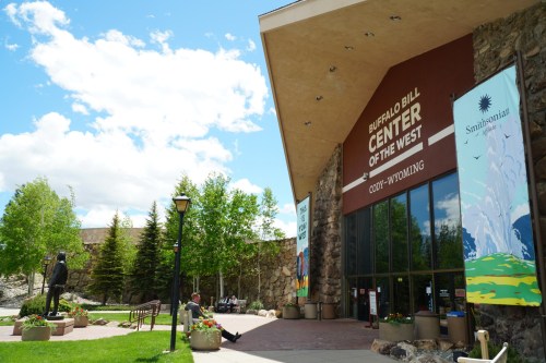 Exterior view of the Buffalo Bill Center of the West in Cody, Wyoming, featuring a stone facade and green landscaping.