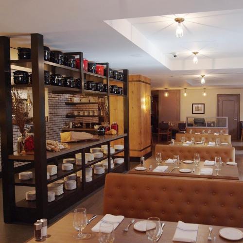 A cozy restaurant interior featuring wooden decor, neatly arranged tables, and shelves with cookware.