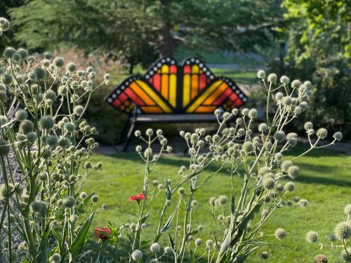 A colorful stained glass bench surrounded by green grass and flowering plants in a garden setting.