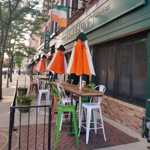 Outdoor seating area of Jameson's Irish pub, featuring colorful umbrellas and a brick facade.