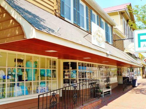 A charming storefront with large windows displaying blue and white decor, set in a sunny, inviting street.