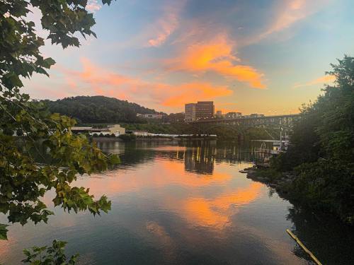A serene river scene at sunset, with colorful clouds reflecting on the water and a bridge in the background.