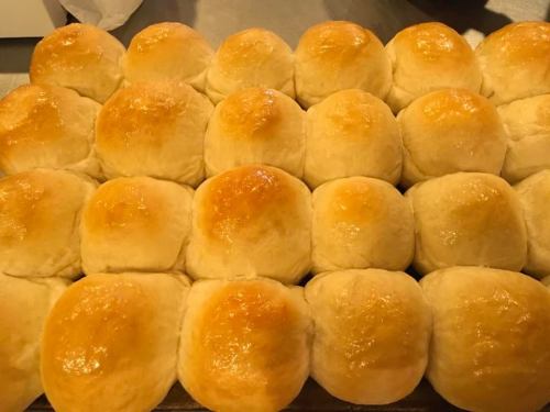 A tray of golden-brown, freshly baked dinner rolls arranged in neat rows.