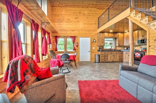 Cozy wooden cabin interior with red accents, featuring a living area, kitchen, and dining space.