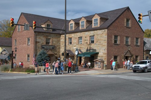 Historic building with stone and brick exterior, featuring a clock and people gathered outside, near traffic lights.