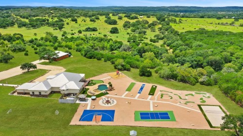 Aerial view of a spacious outdoor recreational area with a pool, sports courts, mini-golf, and lush green surroundings.